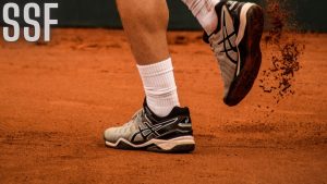Man Wearing Black-and-white Asics Athletic Shoes Holding Racket